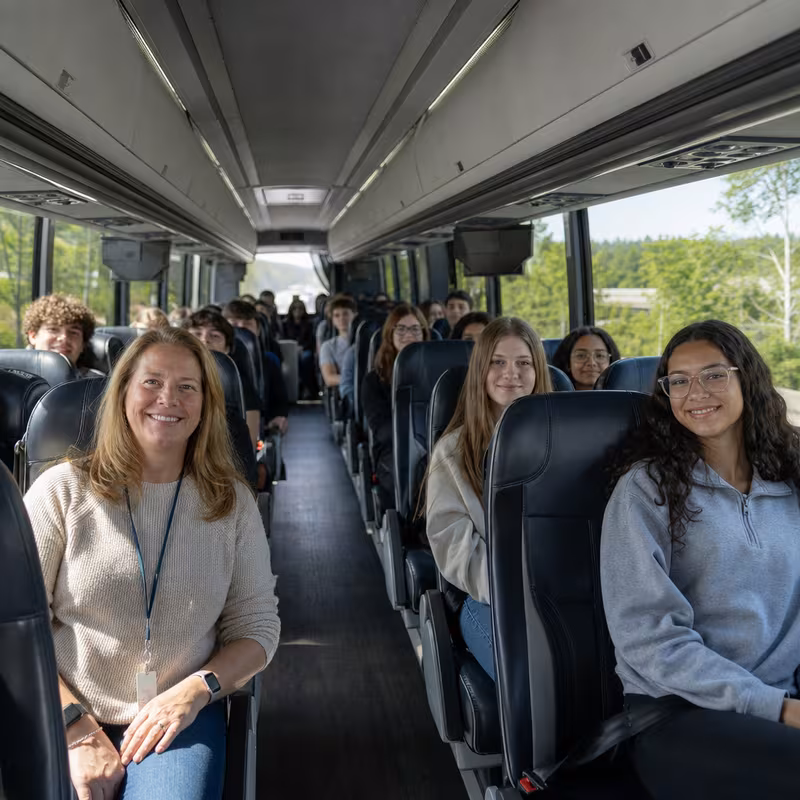Group boarding a white charter bus for School Transportation transportation in Glendale